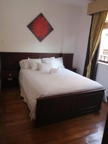 a bedroom with a large bed with white sheets and pillows at San Jose hospedaje in Cuenca