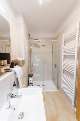 a white bathroom with a shower and a sink at Apartma Castrum Vini in Ajdovščina