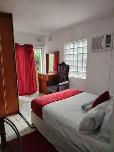 a bedroom with a bed and a chair and a desk at Lytton Cresent B&B in Pinetown