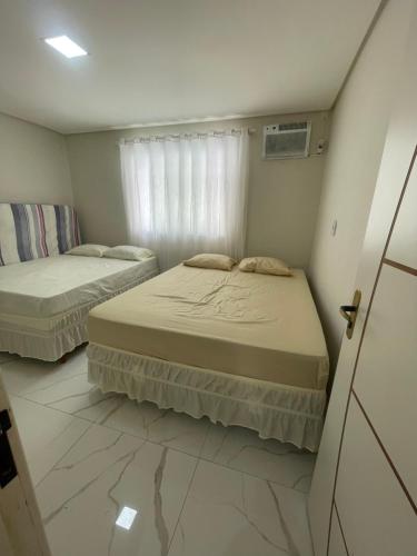 two beds in a small room with a window at Brisa Mar in Canavieiras