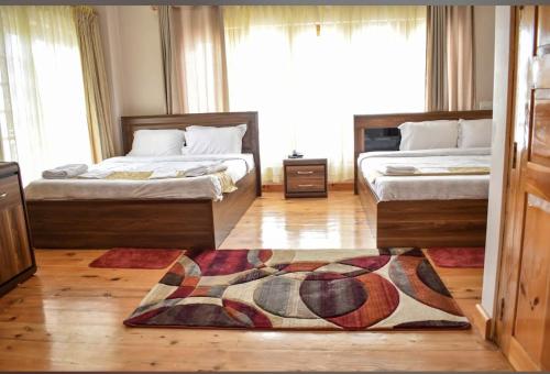 ein Schlafzimmer mit zwei Betten und einem Teppich auf dem Boden in der Unterkunft GaiaYuel in Thimphu