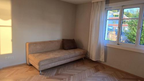 a couch sitting in a room with a window at Sunset View Apartment Bregenz Bodensee in Bregenz
