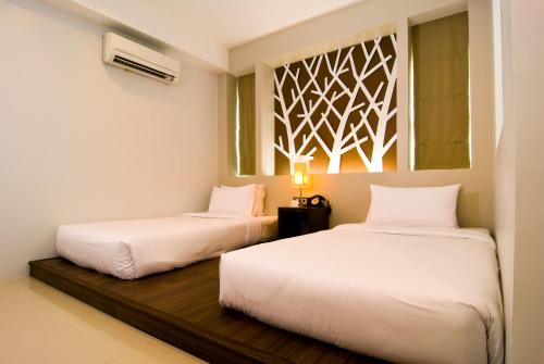 two beds in a room with white sheets at The Album Hotel in Patong Beach