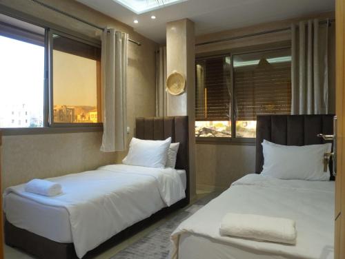 two beds in a room with two windows at Shams House in Imsouane