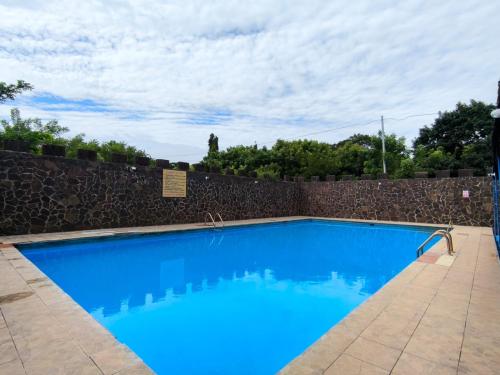een groot blauw zwembad met een stenen muur bij Hotel Corazon de Granada in Granada