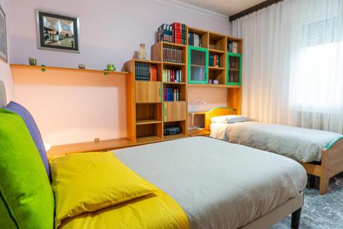 ein Schlafzimmer mit 2 Betten und einem Bücherregal in der Unterkunft Casa Luna appartamento alle Terme con 3 Camere da Letto vicino alla Stazione in Montegrotto Terme