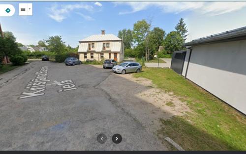 a parking lot with cars parked in front of a house at Barons Street Apartment in Dobele