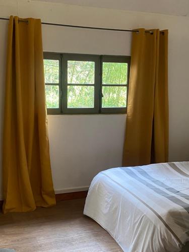 a bedroom with a bed and two windows at Charmant chalet in Auffargis