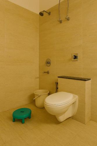 a bathroom with a toilet and a green stool at 2 Bhk Mayra Homes in Raipur