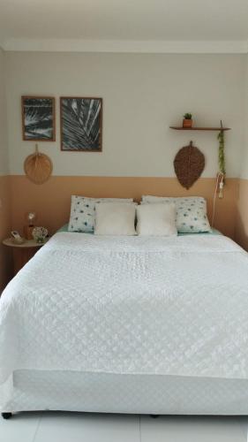 a bedroom with a large white bed with blue pillows at Seu refúgio em Maragogi in Maragogi
