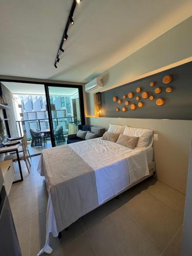 a bedroom with a large bed and a living room at Nomar Carneiros - Flat Beira-mar in Tamandaré