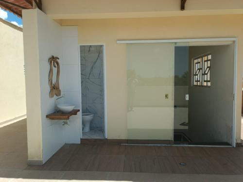 een badkamer met toilet en glazen deur bij Seu refúgio em Maragogi in Maragogi