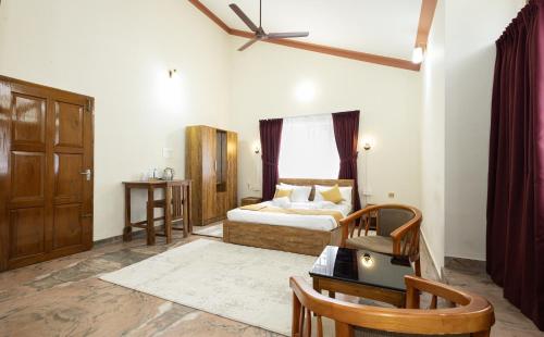 a bedroom with a bed and a table and a window at Bloom Fort Villa in Kannur