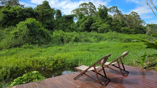 Twee houten stoelen staan op een terras vlakbij een veld. bij Parakreek Apartments in Boxel