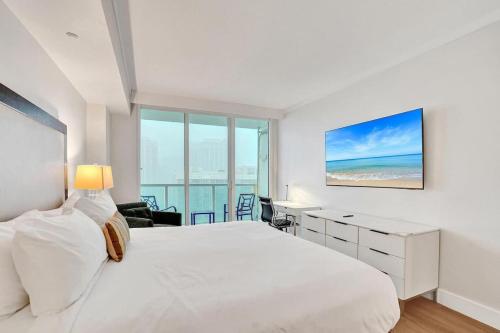 a white bedroom with a large bed and a desk at Bright Studio at The Arya City and Bay Access in Miami