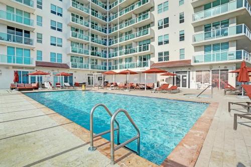 a pool with chairs and umbrellas in front of a building at Bright Studio at The Arya City and Bay Access in Miami