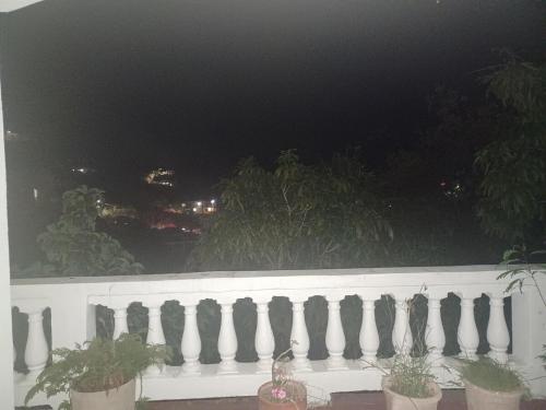 une clôture blanche avec des plantes en pot sur un balcon la nuit dans l'établissement Come Chill on the Hill, à Nazareth