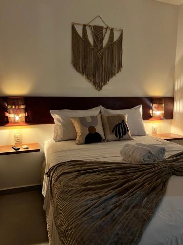 a bedroom with a large bed with a person sitting on it at Toca do Lobo in Pipa