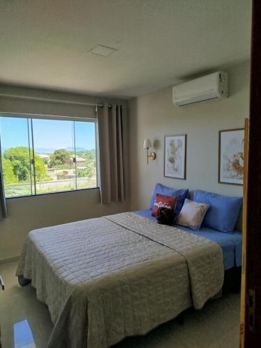 a bedroom with a bed and a large window at 05 minutos da praia - Casa Superior céu azul Buzios in Búzios
