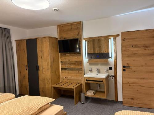 een slaapkamer met een wastafel en een badkamer met houten wanden bij Alpenresort Panorama in Oberperfuss
