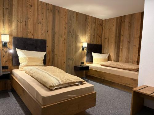 twee bedden in een kamer met houten wanden bij Alpenresort Panorama in Oberperfuss
