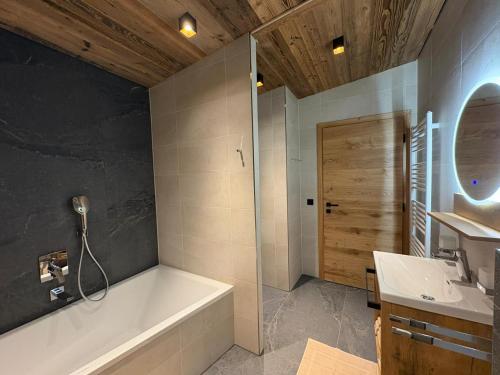 a bathroom with a bath tub and a sink at Alpenresort Panorama in Oberperfuss