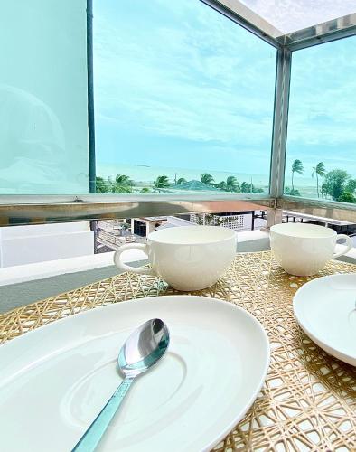 einen Tisch mit weißen Platten, Schalen und einem Löffel in der Unterkunft เดอะซันเซ็ท บางแสน Exclusive Top Floor in Chon Buri