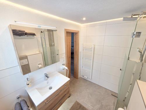 a white bathroom with a sink and a mirror at am Mühlbach - Ferienwohnungen Luttinger in Bichlbach