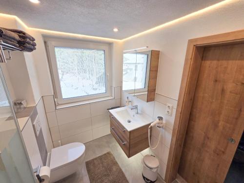 a bathroom with a toilet and a sink and a window at am Mühlbach - Ferienwohnungen Luttinger in Bichlbach
