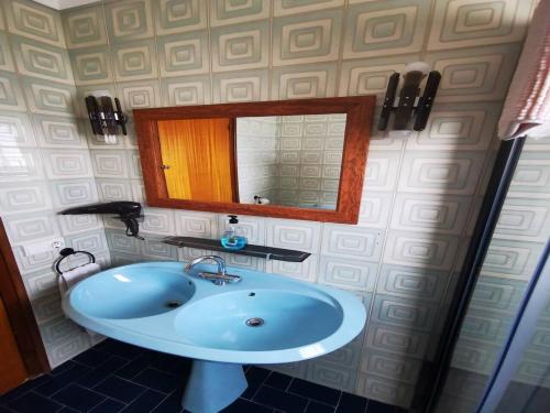 a bathroom with a blue sink and a mirror at Villa Can Raurell Casa rural para 14 en Girona in Sant Feliu de Buixalleu