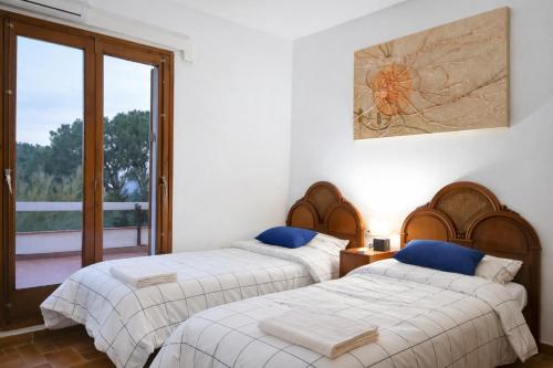 two beds in a room with a balcony at Villa Can Raurell Casa rural para 14 en Girona in Sant Feliu de Buixalleu