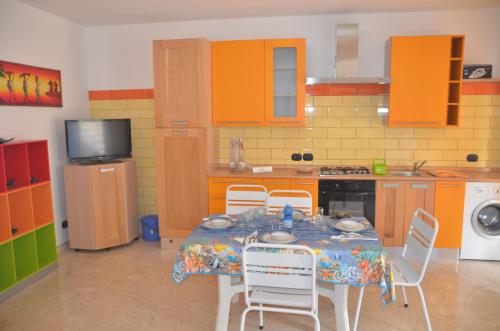 a kitchen with a table with chairs and a kitchen with orange cabinets at Taormina Bay Lucia's House Roccalumera in Roccalumera