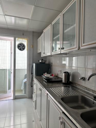 une cuisine avec des armoires blanches et un évier dans l'établissement Downtown Private room, à Abu Dhabi