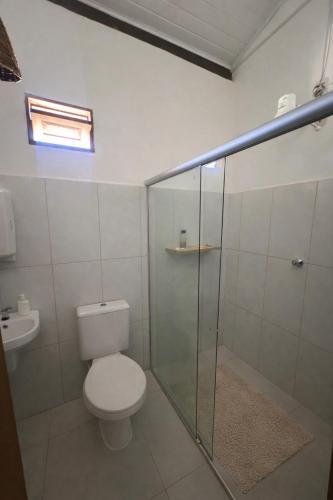 a bathroom with a toilet and a glass shower at Recanto Caraíva in Caraíva