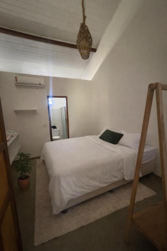 a bedroom with a white bed and a potted plant at Recanto Caraíva in Caraíva
