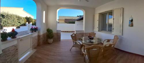 ein Wohnzimmer mit Tisch und Stühlen und einem Fenster in der Unterkunft Villa Rosaria Triscina di Selinunte in Triscina