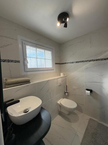 a bathroom with a toilet and a sink and a window at Maison d'hôtes - La Forge de Clermont in Clermont