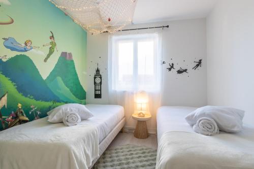 twee bedden in een kamer met een muurschildering. bij Sleep & Cozy Disneyland in Coupvray