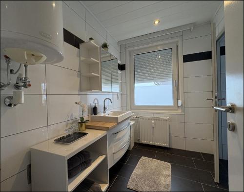 een witte keuken met een wastafel en een raam bij Sankt Veit Apartment in Sankt Veit an der Glan