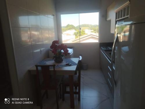 a small kitchen with a table and a window at Aconchego Litorâneo 2 in Piçarras