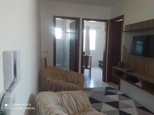 a living room with two chairs and a flat screen tv at Aconchego Litorâneo 2 in Piçarras