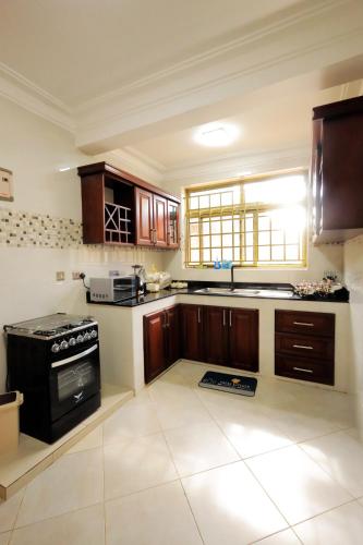 een grote keuken met houten kasten en een fornuis bij Homes by her in Entebbe
