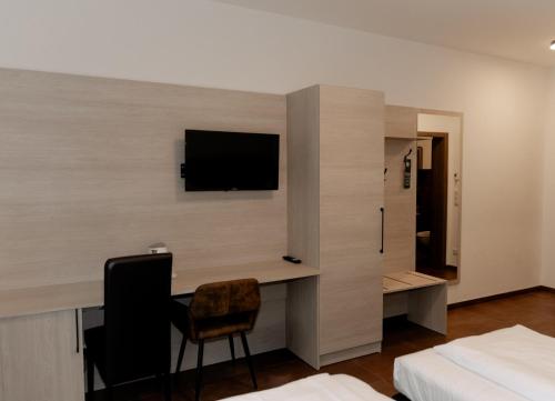 een slaapkamer met een bureau en een tv aan de muur bij Ayhan Hotel in Burgdorf