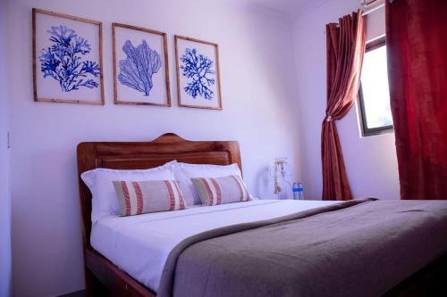 une chambre avec un lit avec quatre tableaux au mur dans l'établissement Alojamento Local - Amor e Mar, à Luanda