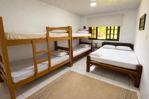 una stanza con tre letti a castello e una finestra di Casa da Índia - Pousada Jussara a Joinville