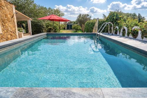 a swimming pool with a red umbrella in a yard at Es Marroig Villa y Spa in Llucmajor