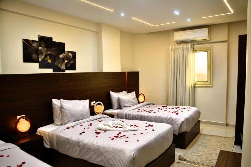 a hotel room with two beds with red flowers on them at Makan Pyramids Hotel in Cairo
