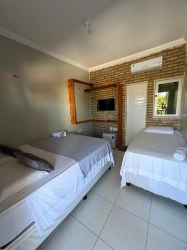 een slaapkamer met twee bedden en een bakstenen muur bij Kairos Beach Hotel in Camocim