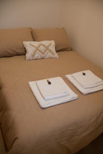 een bed met twee witte handdoeken erop bij VIELA Guest House T2 in Barcelos