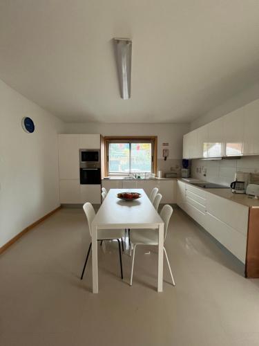 een witte keuken met een witte tafel en stoelen bij Alojamento Local Pando in Aveleda